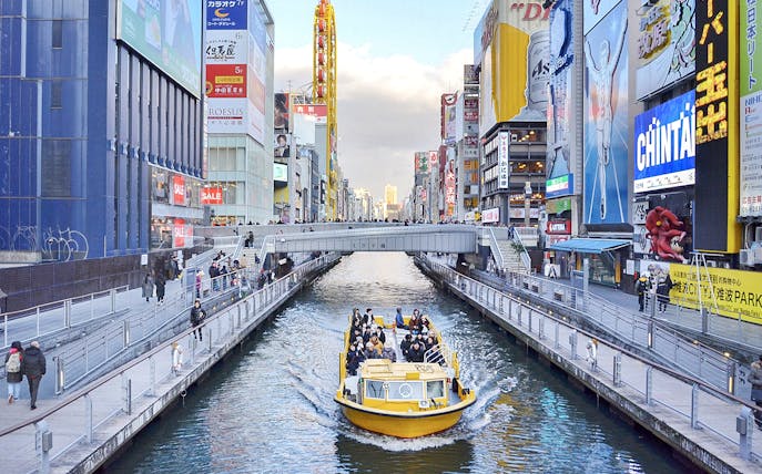 Tombori River Cruise boat navigating through Osaka's vibrant Dotonbori district.