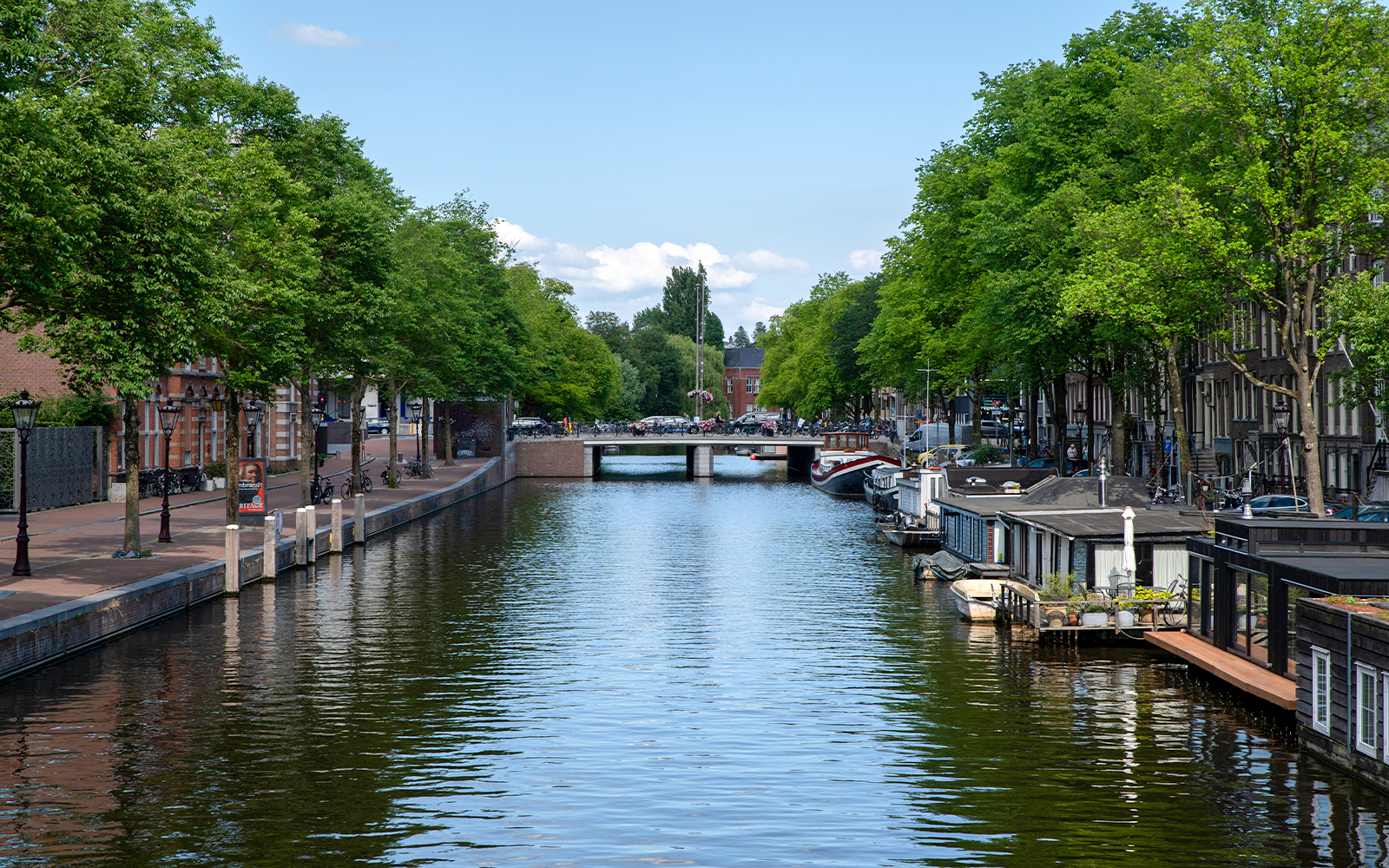 Amsterdam canal with houseboats and a bridge in the background.