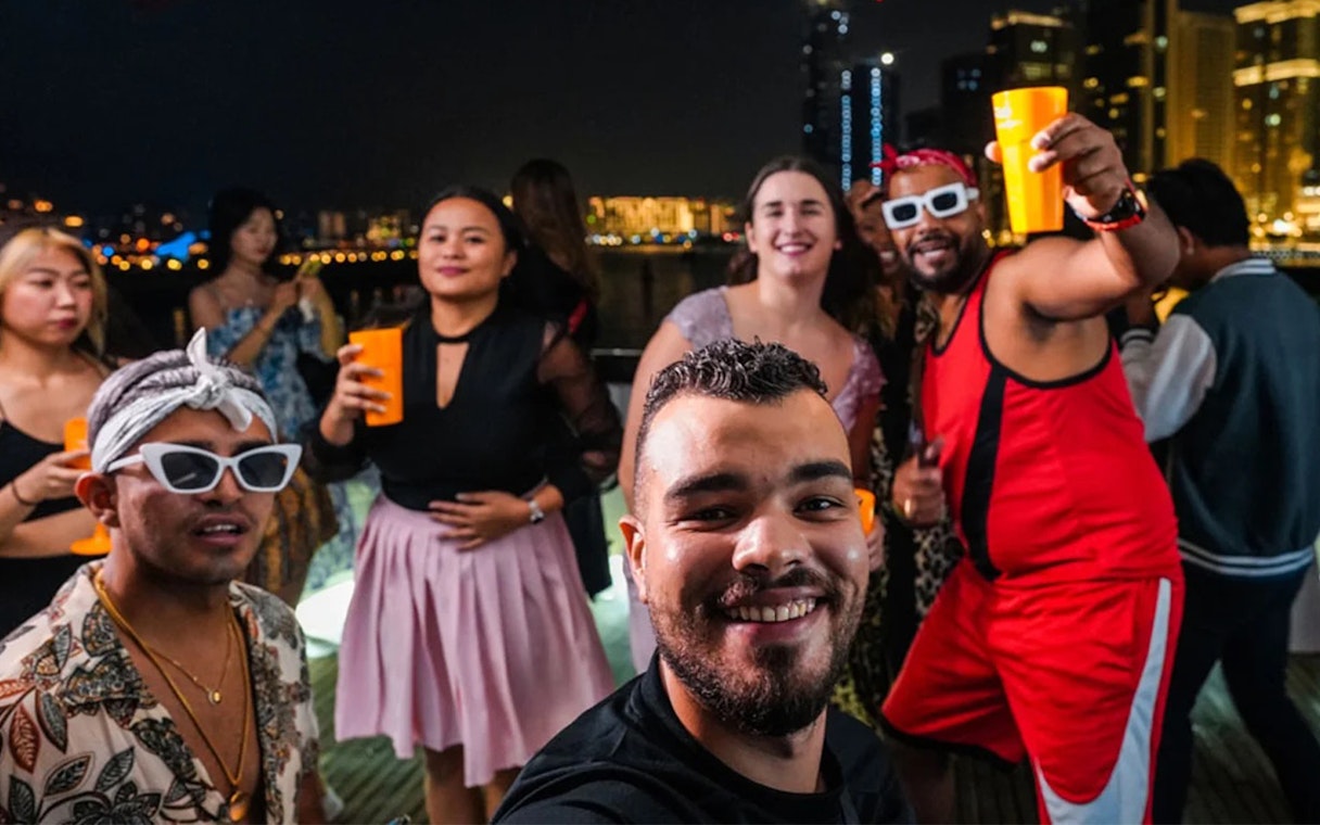 Friends enjoying a night party on a yacht at Dubai Marina.
