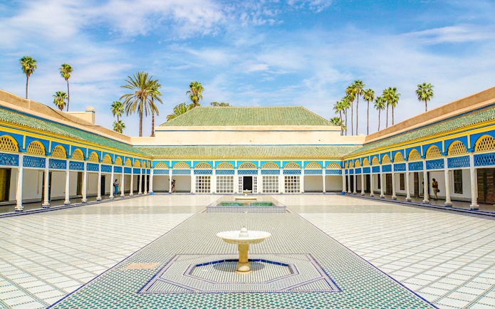 Bahia Palace courtyard with fountain and palm trees in Marrakech, Morocco.