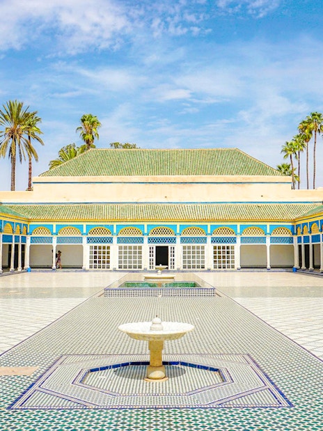 Bahia Palace courtyard with fountain and palm trees in Marrakech, Morocco.