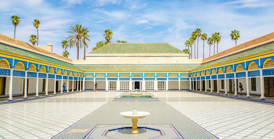 Bahia Palace courtyard with fountain and palm trees in Marrakech, Morocco.