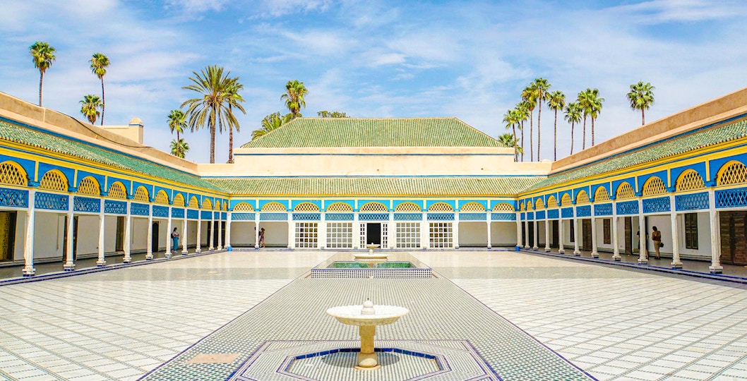 Bahia Palace courtyard with fountain and palm trees in Marrakech, Morocco.