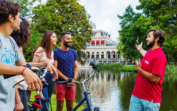 Cyclists riding along a canal in Amsterdam, showcasing city architecture and vibrant street life.