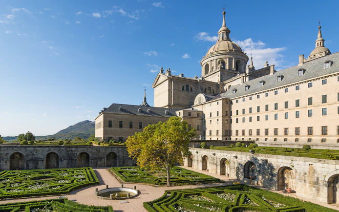 Royal Site of San Lorenzo de El Escorial with courtyard and garden view.