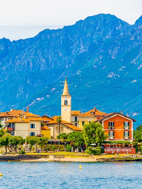 Island village with church tower and colorful buildings on Isole Borromee, Italy, viewed from the water.