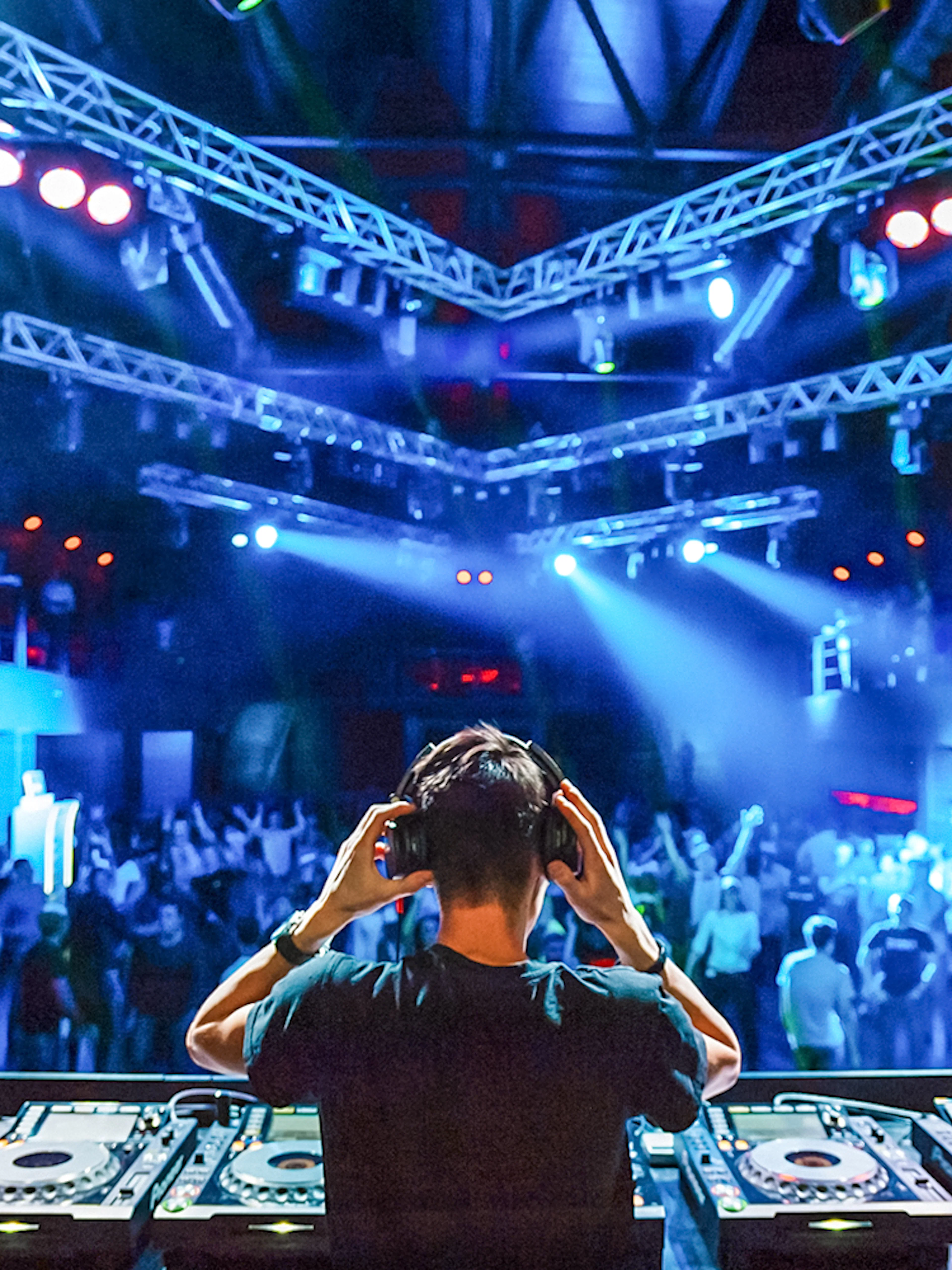 DJ wearing headphones performing at a vibrant nightclub.