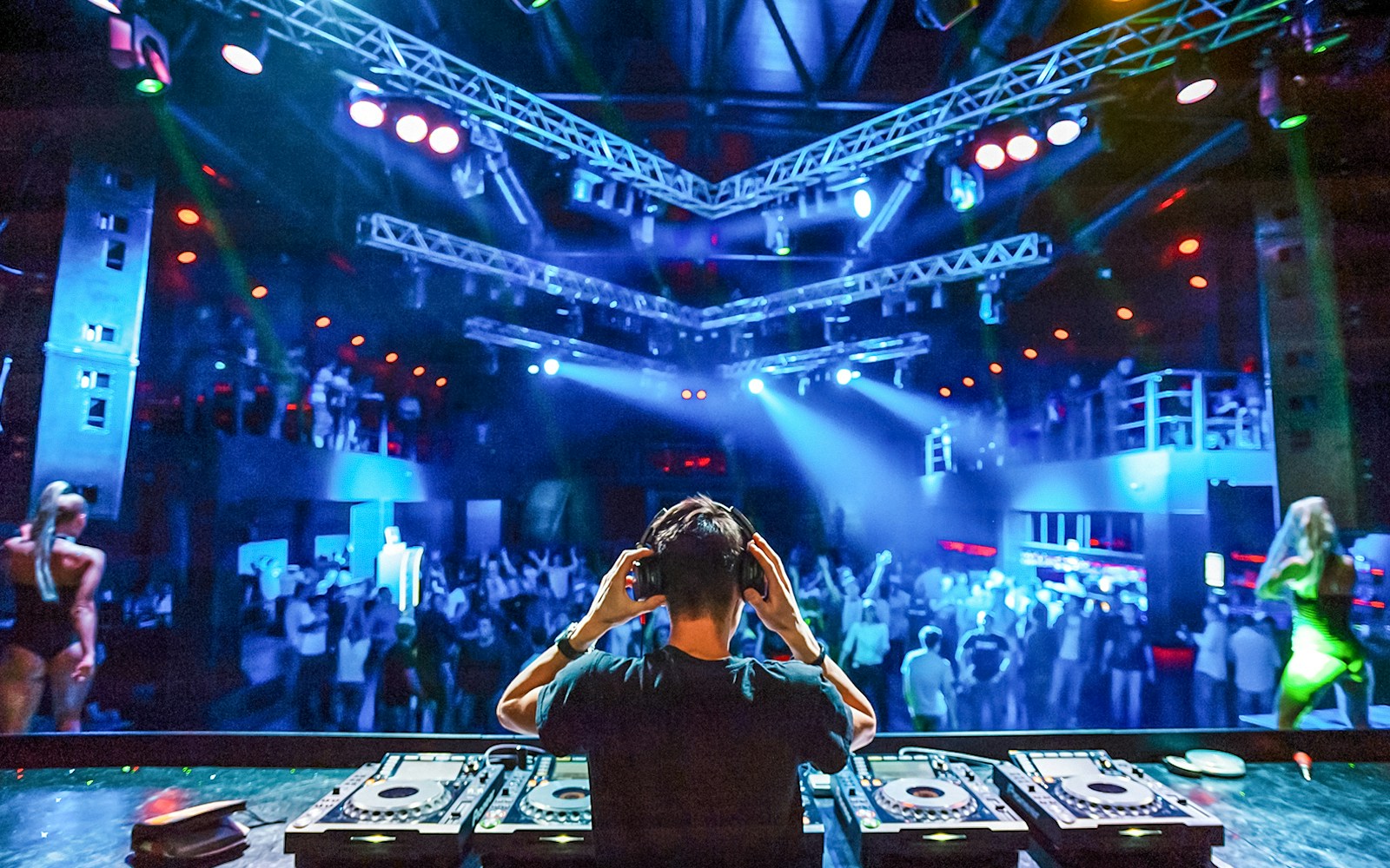 DJ wearing headphones performing at a vibrant nightclub.