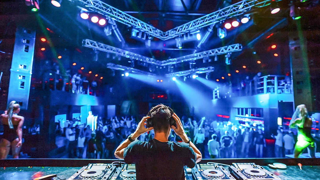 DJ wearing headphones performing at a vibrant nightclub.