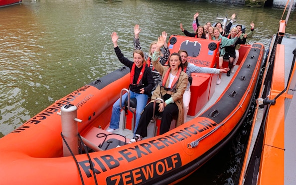 Group enjoying Rotterdam Harbour tour on RIB speedboat, waving and smiling.