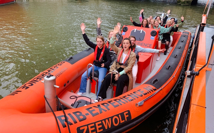 Group enjoying Rotterdam Harbour tour on RIB speedboat, waving and smiling.