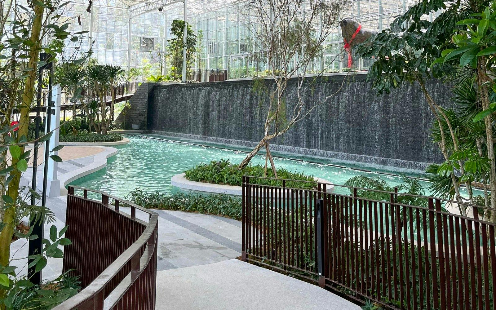 Waterfall and pond at Eufloria Gardens & Sculpture Park with lush greenery.
