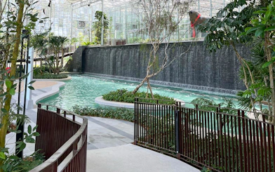 Waterfall and pond at Eufloria Gardens & Sculpture Park with lush greenery.