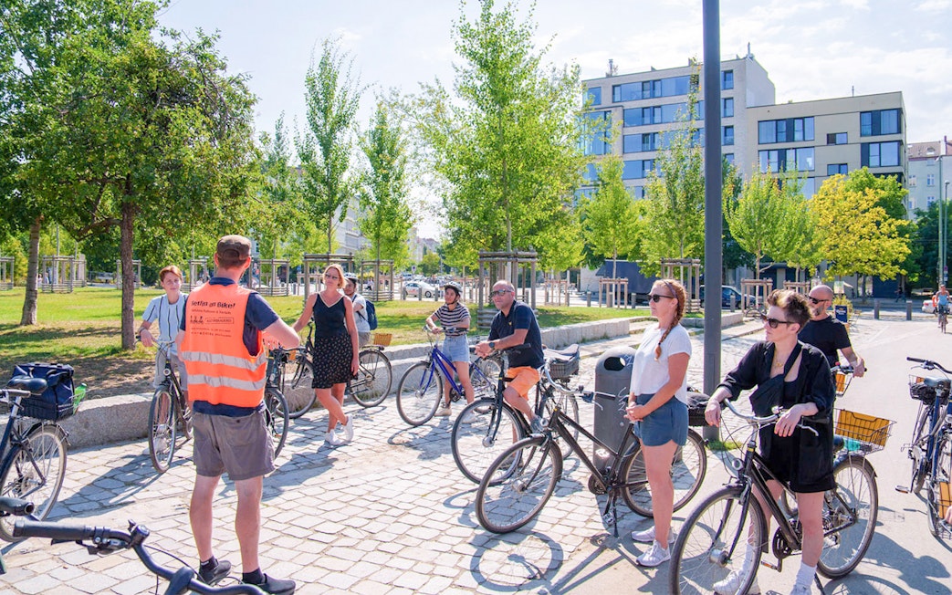 Group of cyclists listening to a guide during a Berlin Wall bike tour.