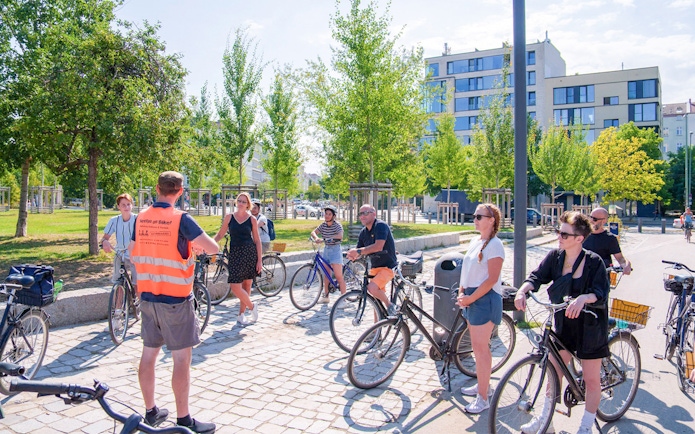 Group of cyclists listening to a guide during a Berlin Wall bike tour.