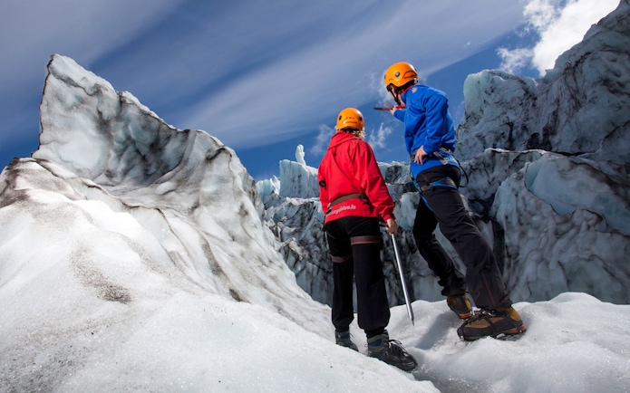 Guests hiking on Vatnajökull Glacier, Iceland, wearing helmets and crampons.