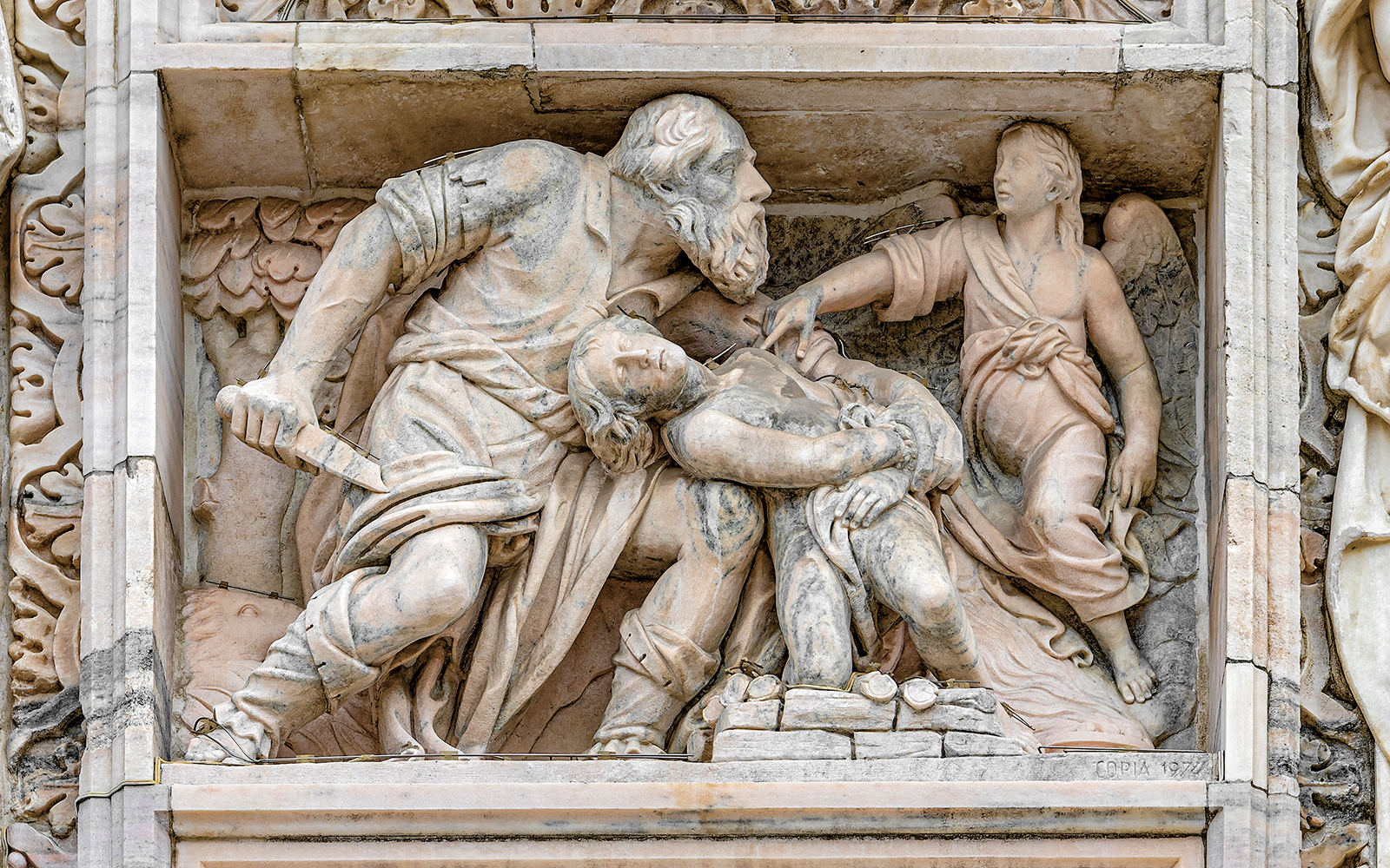 Relief sculpture on Milan Duomo depicting biblical scene with angel and figures.