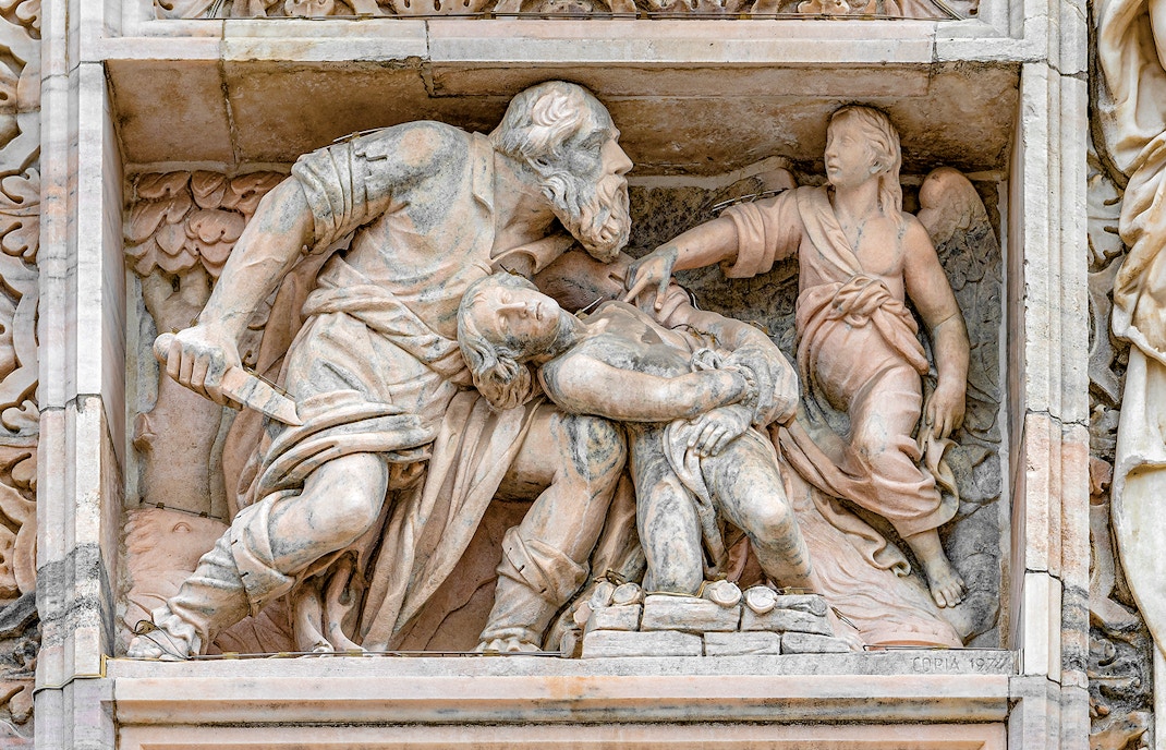 Relief sculpture on Milan Duomo depicting biblical scene with angel and figures.