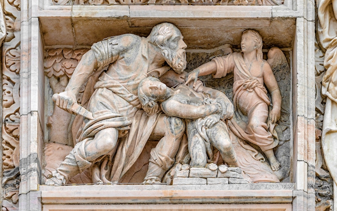 Relief sculpture on Milan Duomo depicting biblical scene with angel and figures.