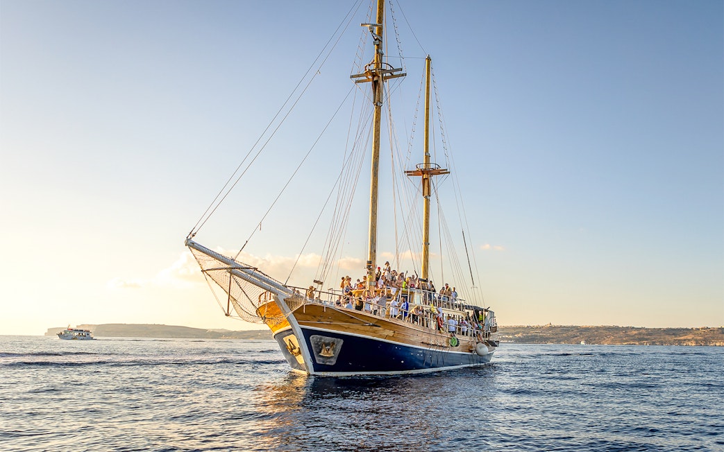 Cruise ship sailing near Gozo and Comino Islands at sunset.