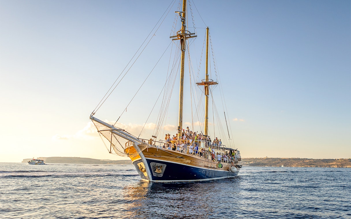 Cruise ship sailing near Gozo and Comino Islands at sunset.