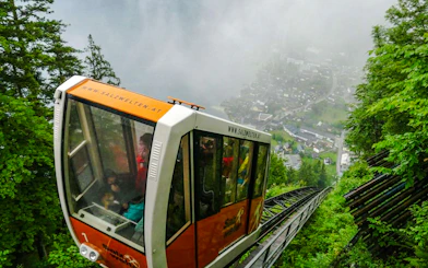 Funicular ascending to Hallstatt Salt Mine, surrounded by lush greenery and misty views, Salzburg.