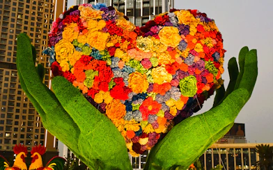 Floral heart sculpture held by green hands at Dubai Garden Glow.