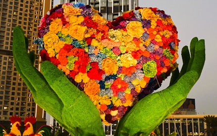 Floral heart sculpture held by green hands at Dubai Garden Glow.