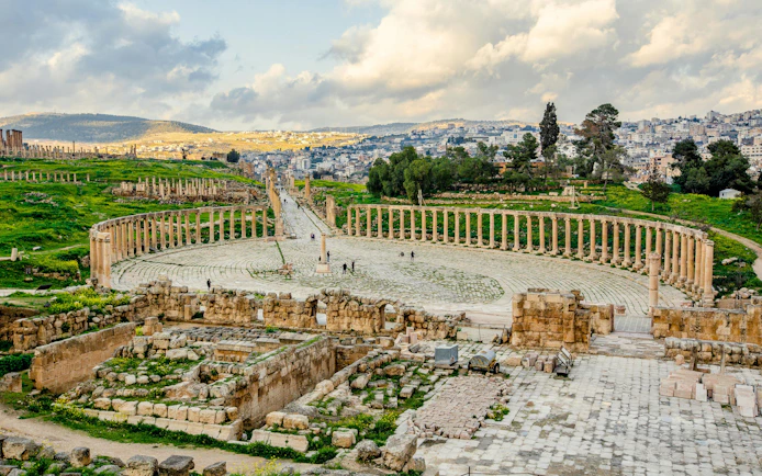 Roman ruins with colonnade in Jerash, Jordan, showcasing ancient architecture and cityscape.