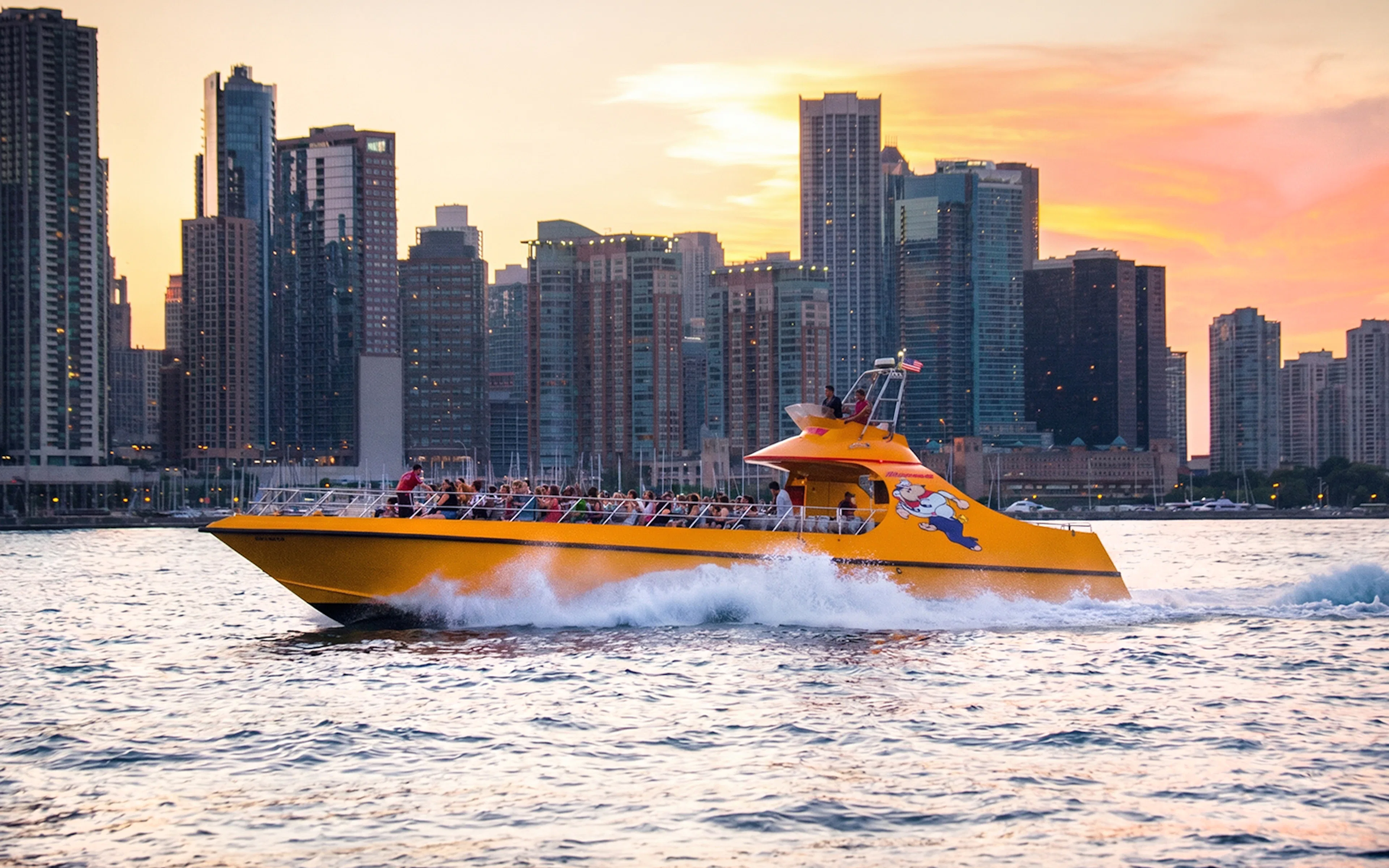 Yellow boat cruising on Lake Michigan with Chicago skyline at sunset.