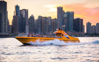 Yellow boat cruising on Lake Michigan with Chicago skyline at sunset.