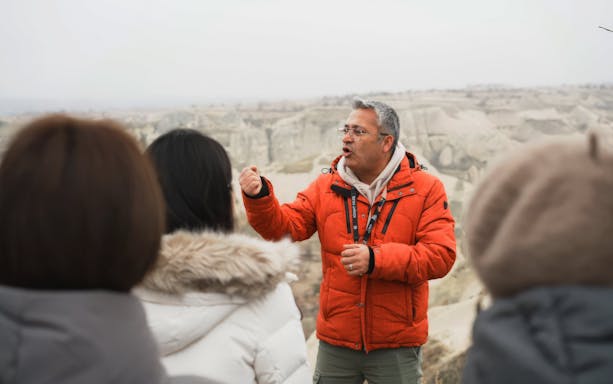 Guide explaining rock formations to visitors at Göreme National Park.