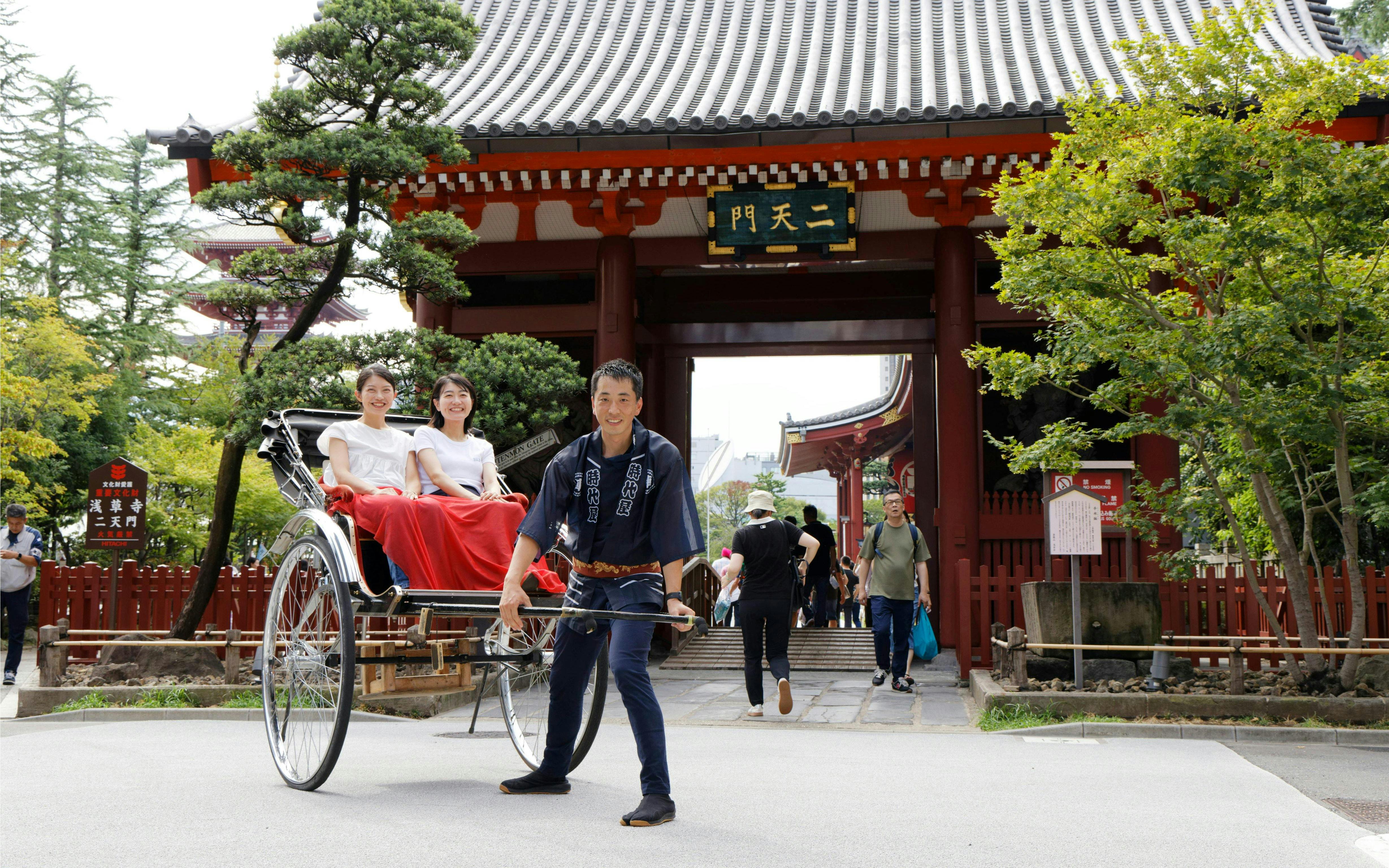 Tourists in rickshaw near temple gate during Japanese Rickshaw Experience in Asakusa.