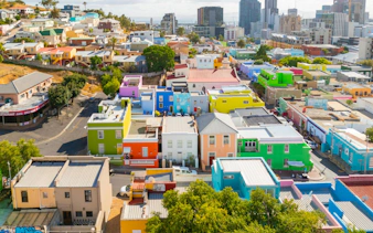 Colorful houses in Bo-Kaap, Cape Town, with city skyline in the background.