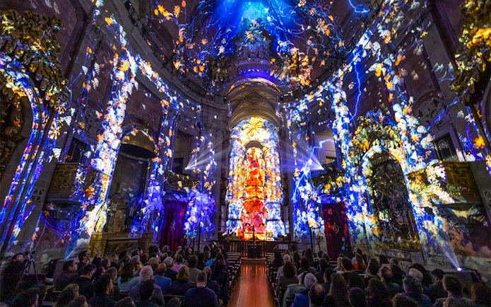 Spectacular light show at Spiritus, Clérigos Church, Porto, with audience seated inside.