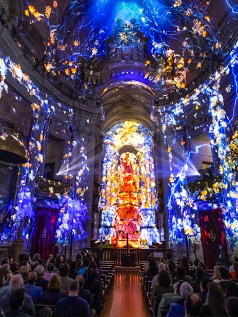 Spectacular light show at Spiritus, Clérigos Church, Porto, with audience seated inside.