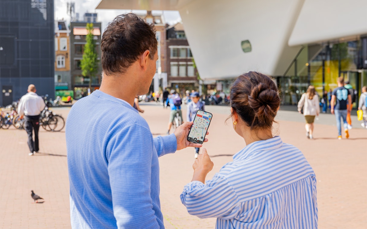 Couple using I amsterdam City Card app near museum entrance in Amsterdam.