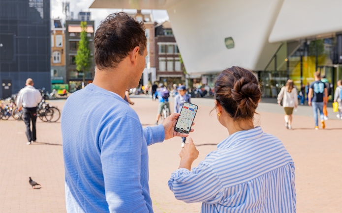 Couple using I amsterdam City Card app near museum entrance in Amsterdam.