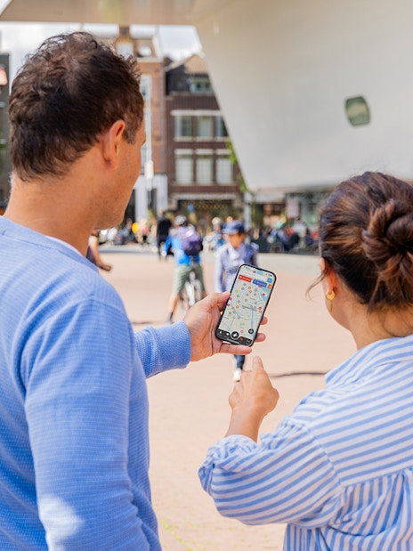 Couple using I amsterdam City Card app near museum entrance in Amsterdam.