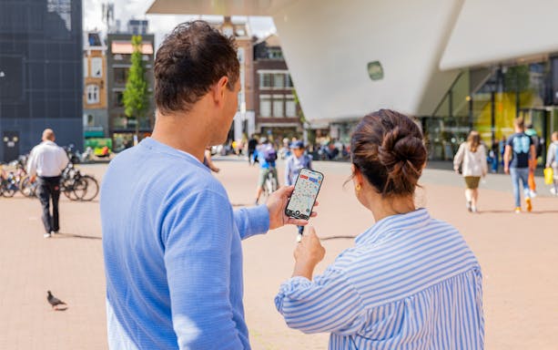 Couple using I amsterdam City Card app near museum entrance in Amsterdam.