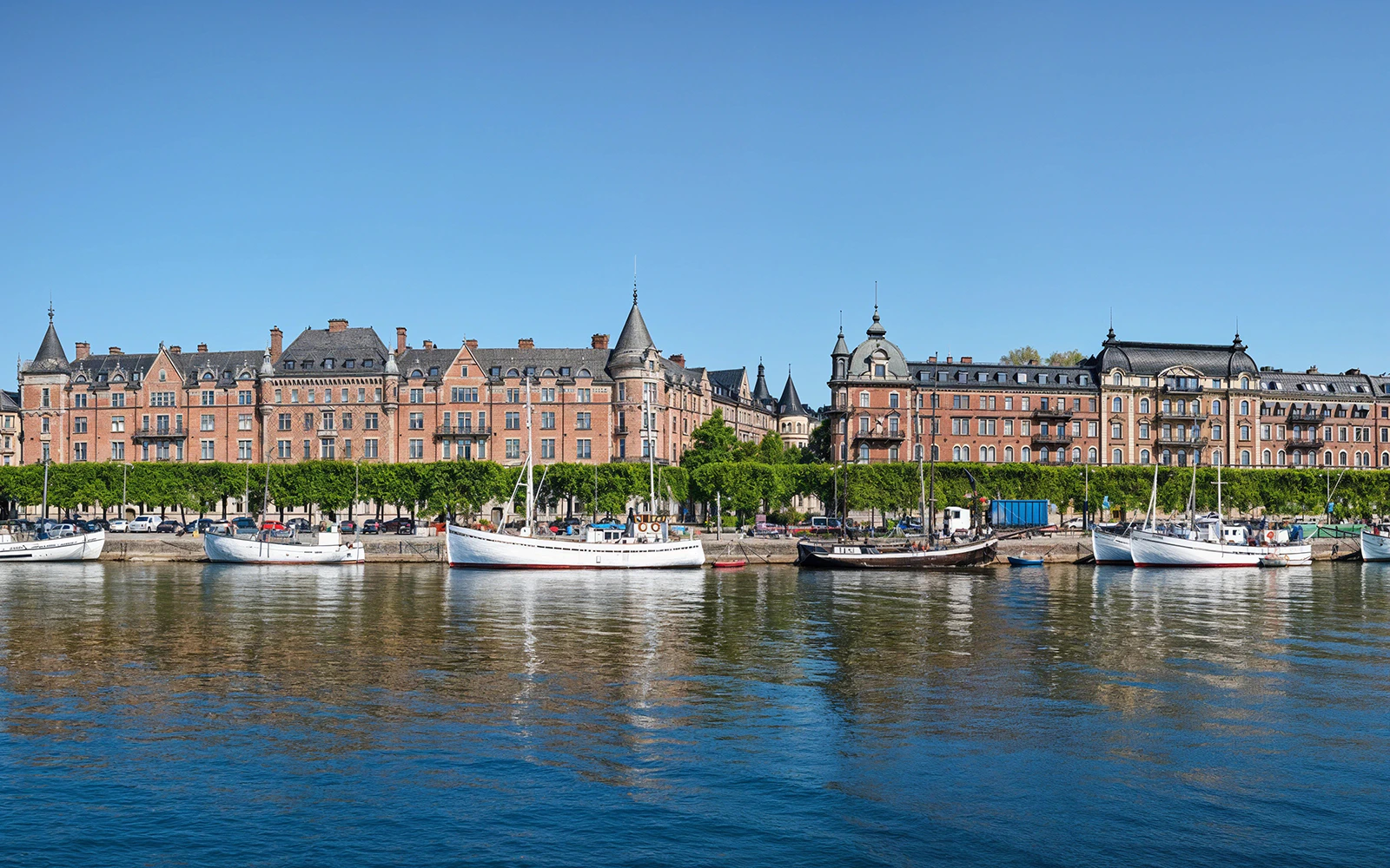 Boats docked at the pier along Strandvägen, Stockholm with historic buildings in the background.