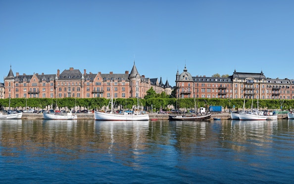 Boats docked at the pier along Strandvägen, Stockholm with historic buildings in the background.