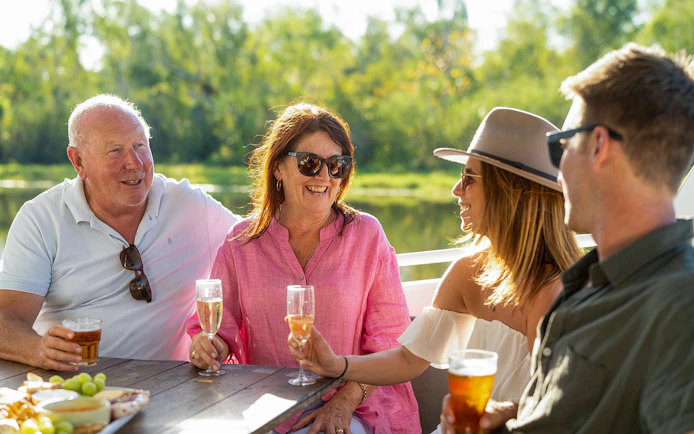 Guests enjoying drinks on a boat tour during the Top End Safari Camp Overnight Tour near Finniss River.