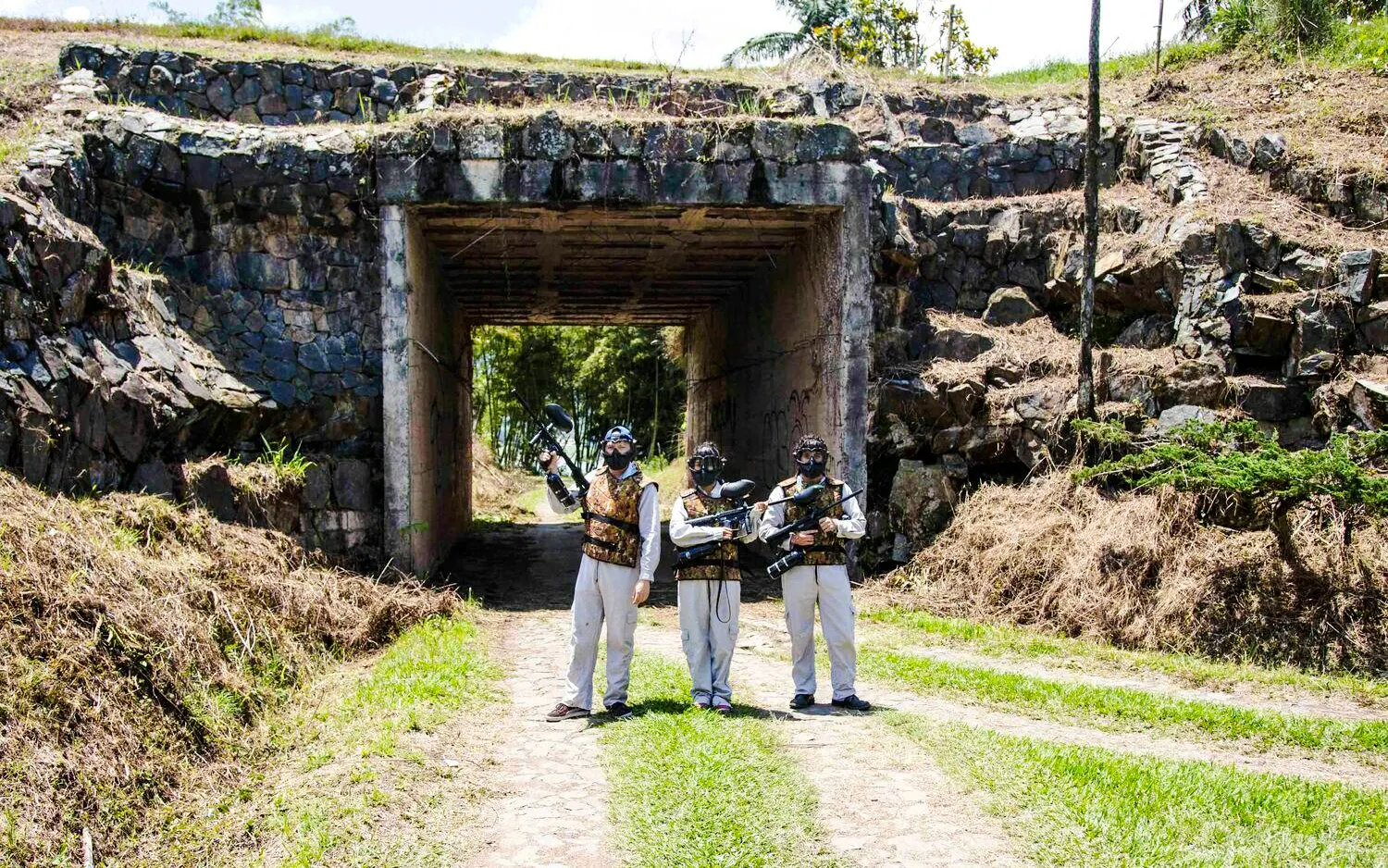 Guests with paintball gear at stone railroad underpass, La Manuela Estate, Guatapé, Colombia.