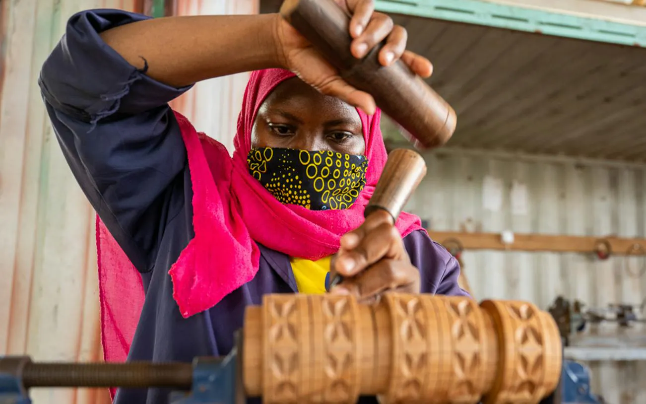 Person crafting wooden design during upcycling workshop in Stone Town, Zanzibar.