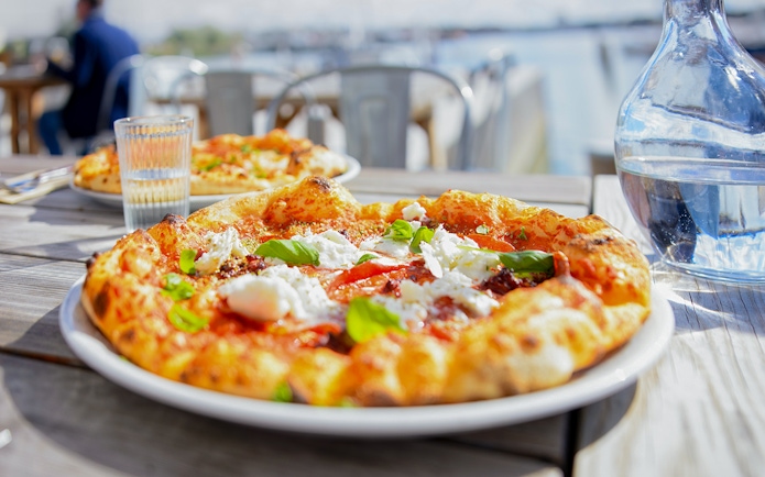 Pizza on table with view of Bay of Naples during Pompeii tour lunch.