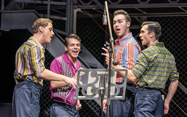 Performers singing on stage in the musical "Jersey Boys.