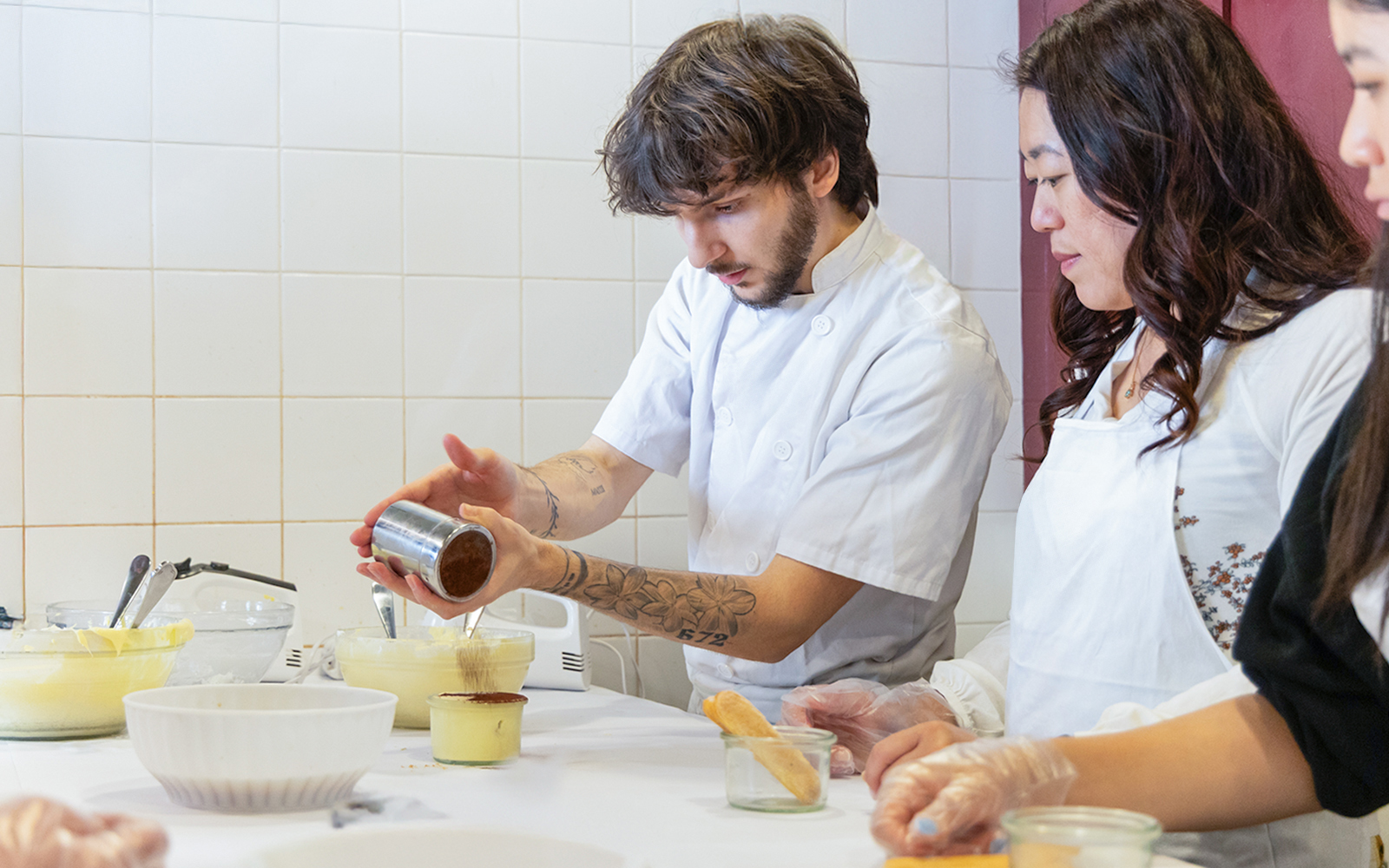 Participants making tiramisu in a Rome cooking class kitchen.