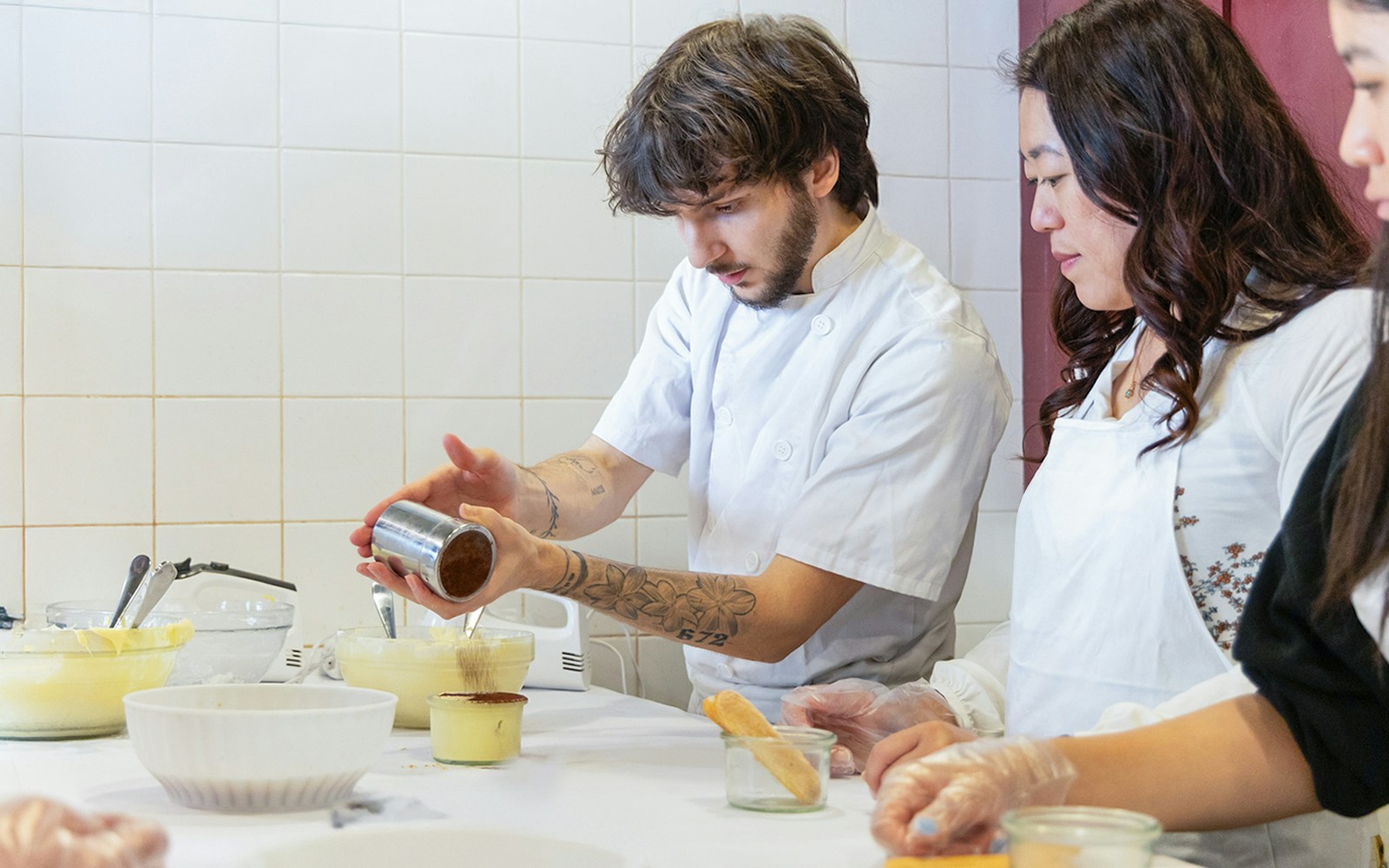 Participants making tiramisu in a Rome cooking class kitchen.