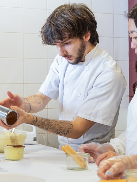 Participants making tiramisu in a Rome cooking class kitchen.